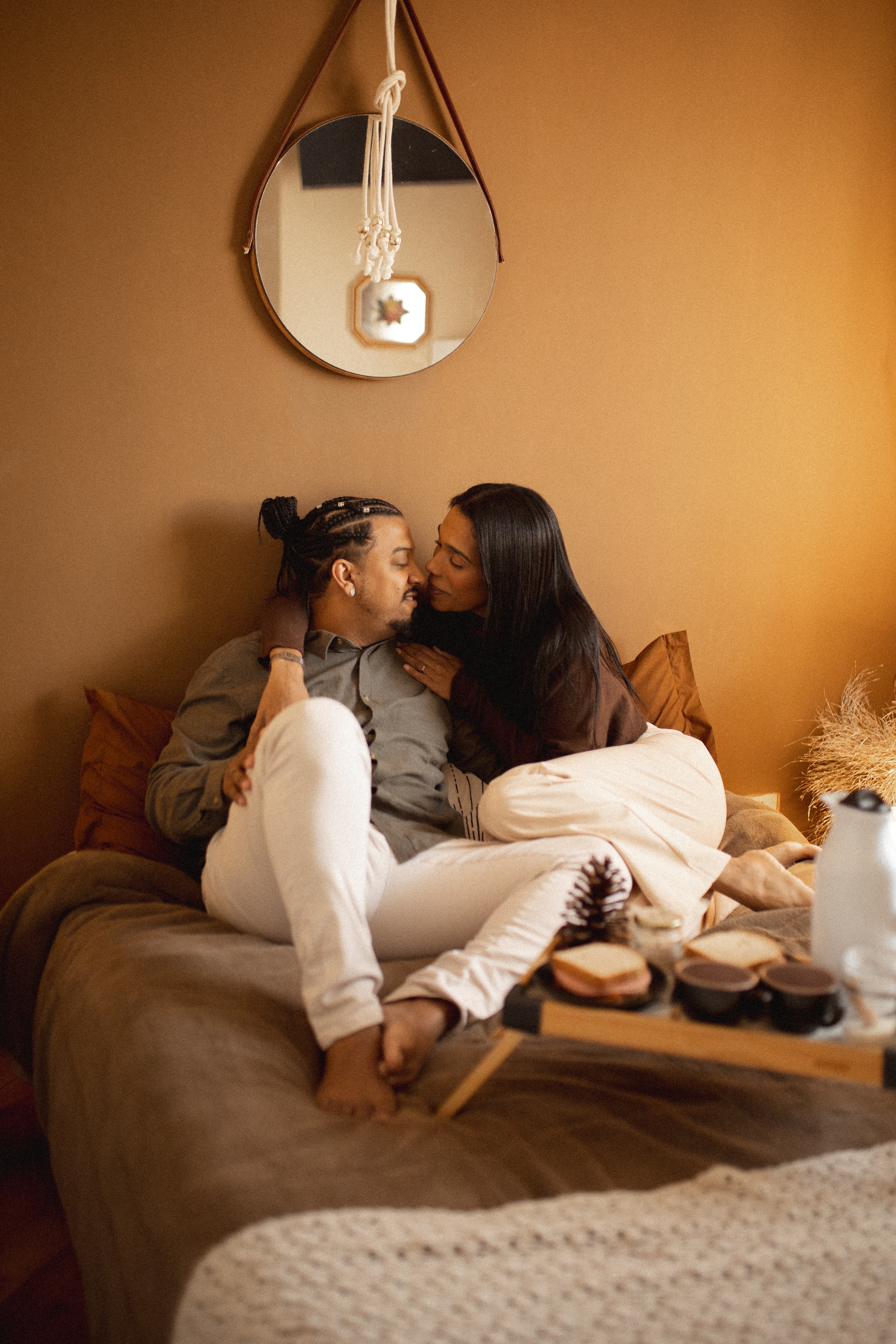 Paula e Erik se aproximam para um beijo na cama, junto à bandeja do café.